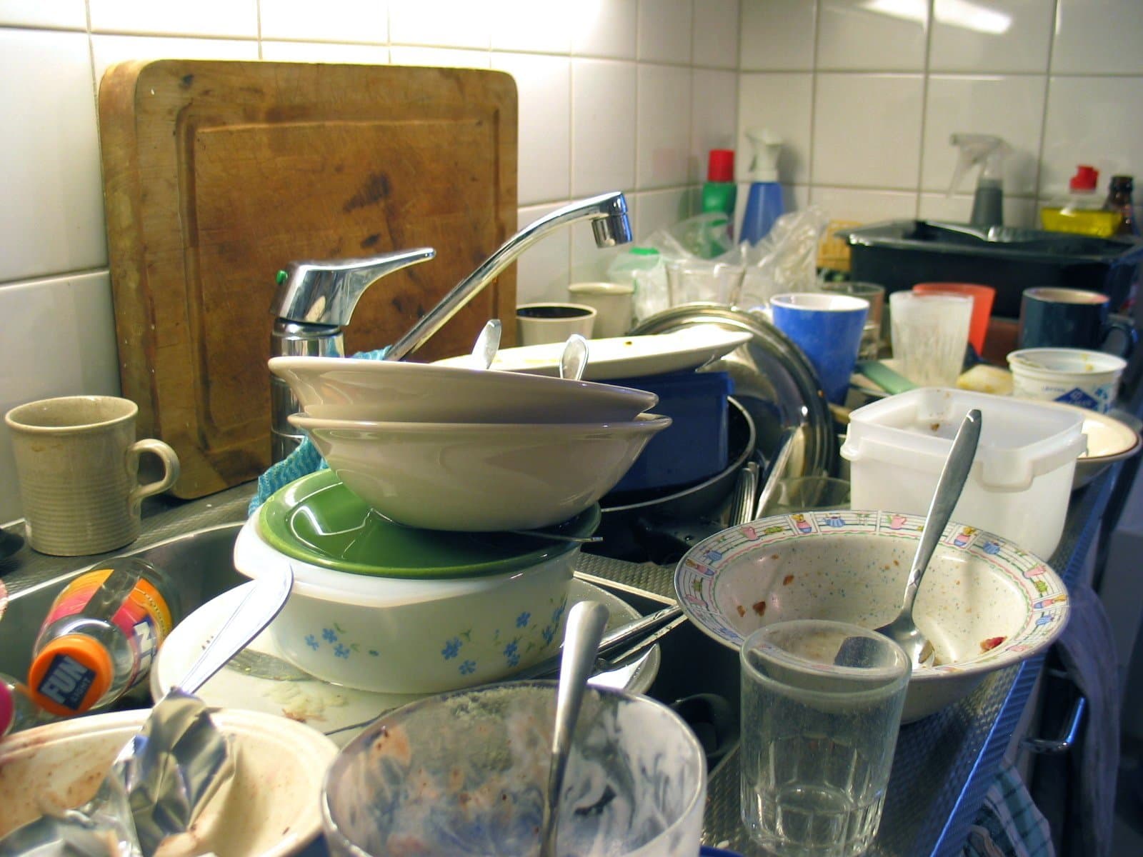 A shared kitchen sink piled high with unwashed bowls, cups and plates